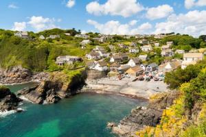 a town on a hill with a body of water at Pebbles in Cadgwith
