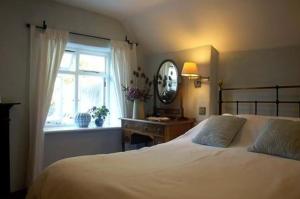 a bedroom with a large white bed and a window at Pebbles in Cadgwith