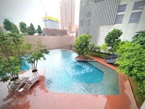 a large swimming pool with chairs in a city at Lucentia residence luxury suites in Kuala Lumpur