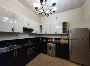 a kitchen with white cabinets and a stainless steel refrigerator at M&W Hostel in Yerevan