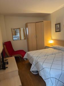a bedroom with a bed and a red chair at Pensión USOA in Zubiri +10 photos
