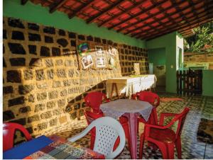 a table and chairs in a room with a brick wall at Suítes Pouso do Sol in Praia de Araçatiba