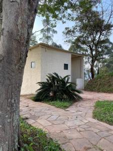 a white building with a tree in front of it at Loft no Sul de Minas in Baependi