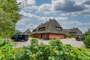 an old house with cars parked in a parking lot at Wattblick in Braderup