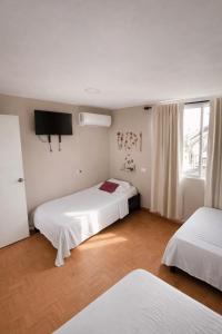 a hotel room with two beds and a television at Seven Nights Hostel Cartagena in Cartagena de Indias +37 photos