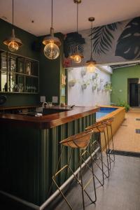 a bar with stools in a room with green walls at Seven Nights Hostel Cartagena in Cartagena de Indias
