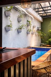 a bar with potted plants on a wall next to a swimming pool at Seven Nights Hostel Cartagena in Cartagena de Indias
