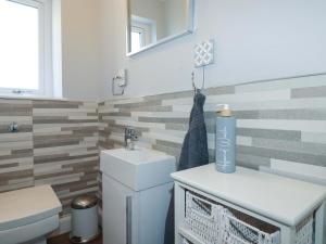 a bathroom with a sink and a toilet and a mirror at Little Pippin in Carlyon Bay +19 photos