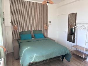 ein Schlafzimmer mit einem großen Bett und blauen Kissen in der Unterkunft Studio Aloe in Dunkerque