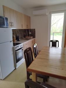 a kitchen with a wooden table and a white refrigerator at Apartmani Bele breze in Adlešiči