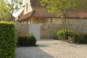 a house with a fence and a brick driveway at Het Weiland Villa Jersey in Damme