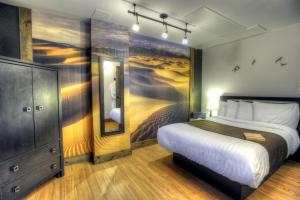 - une chambre avec un lit et une peinture murale dans l'établissement Hotel Continental Centre-Ville, à Val-dʼOr
