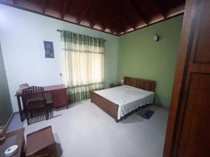 a bedroom with a bed and a desk and a window at Tea Estate Villa in Ratnapura