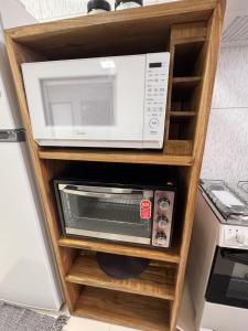a white microwave on a wooden shelf in a kitchen at Refúgio Cachoeira Guaibim in Guaibim