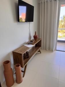 a living room with a tv and a wooden table at Refúgio Cachoeira Guaibim in Guaibim