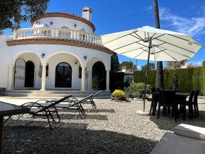 a white building with a table and an umbrella at villa PLAYA RUSTICAL in Miami Platja