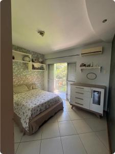 a bedroom with a bed and a television in it at Refúgio Aconchegante com Varanda para Natureza in Resende