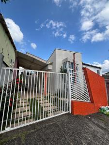a white gate in front of a house at Refúgio Aconchegante com Varanda para Natureza in Resende +2 photos