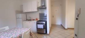 a kitchen with a stove and white cabinets and a table at Alloggio Maia 2 in Biella