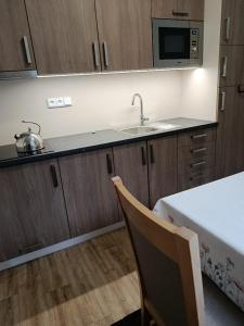 a kitchen with wooden cabinets and a sink and a table at Apartmán s terasou REZIDENCE 300 Všemina in Všemina