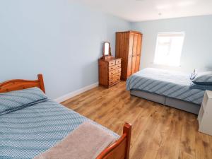 a bedroom with two beds and a dresser in it at Tí Tom Nárta in Trawbaun