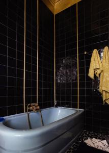 a bath tub in a black tiled bathroom at La Maison Tataouine in Moux