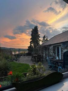 a house with a patio with a sunset in the background at Kirkhill Cottage B&B in Crossmichael