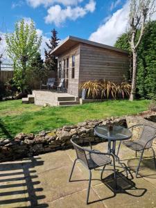 a patio with a table and chairs in front of a house at Honeybee Hideaway in Brompton