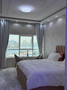 a bedroom with a large bed and a large window at High-floor Luxury Apartment! in Ajman 