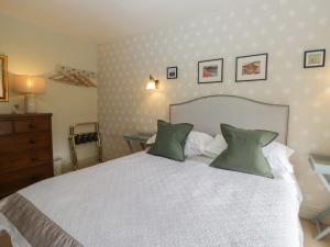 a bedroom with a white bed with green pillows at Gable End in High Yewdale