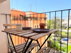 a wooden table with two cups on top of a balcony at Home Syrakos in Syracuse