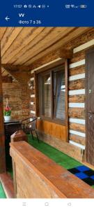 a porch of a log cabin with a bench and a window at ViV in Vorokhta