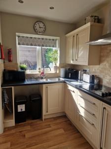 a kitchen with white cabinets and a clock on the wall at Honeybee Hideaway in Brompton