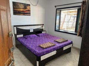 a bedroom with a bed with purple sheets and a window at Beach front in Murud +11 photos
