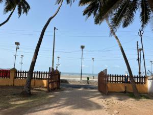 a gate at the beach with a fence and palm trees at Beach front in Murud
