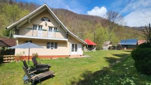 a house with chairs and an umbrella in the yard at Casa de vacanta Julius in Padis