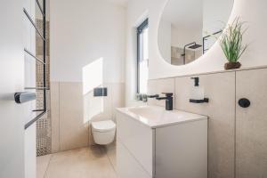 a white bathroom with a sink and a toilet at Strandgeflüster deluxe in Zingst +26 photos
