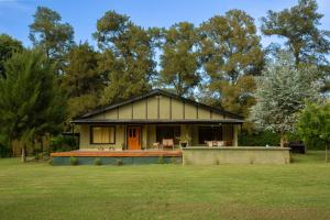 a small house in a field with trees in the background at Las Marukas casas con pileta in San Antonio de Areco