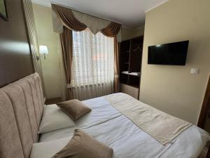 a hotel room with a bed and a television at Ивелия Къща за гости in Dospat