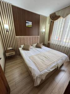 a bedroom with a large white bed with two pillows at Ивелия Къща за гости in Dospat