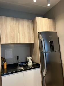 a kitchen with a stainless steel refrigerator and wooden cabinets at Flat no coração de Joinville in Joinville