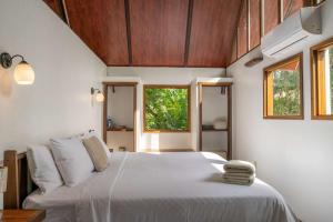 a bedroom with a large white bed and windows at Casa Leon in Talamanca