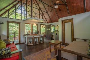 a living room with a ceiling fan and a kitchen at Casa Leon in Talamanca