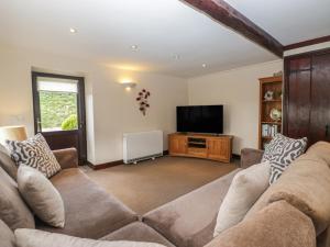 a living room with a couch and a flat screen tv at Woodside Barn in Ulverston