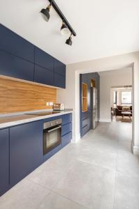 a large kitchen with blue cabinets and a living room at The Wild Atlantic Townhouse in Enniscrone