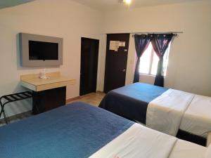 a hotel room with two beds and a television at Hotel Agora in Ensenada