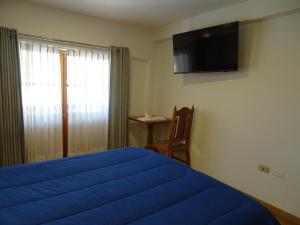 a bedroom with a blue bed and a television on the wall at Artezana Hotel in Cusco