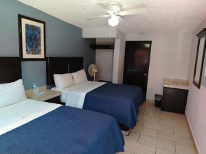 a hotel room with two beds and a ceiling fan at Hotel Agora in Ensenada