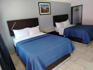 a hotel room with two beds with blue sheets at Hotel Agora in Ensenada +3 photos