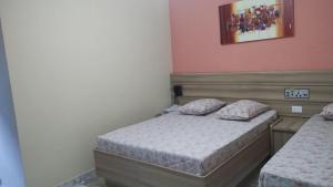 two beds in a small room with pink walls at Hotel Styllus in São Paulo